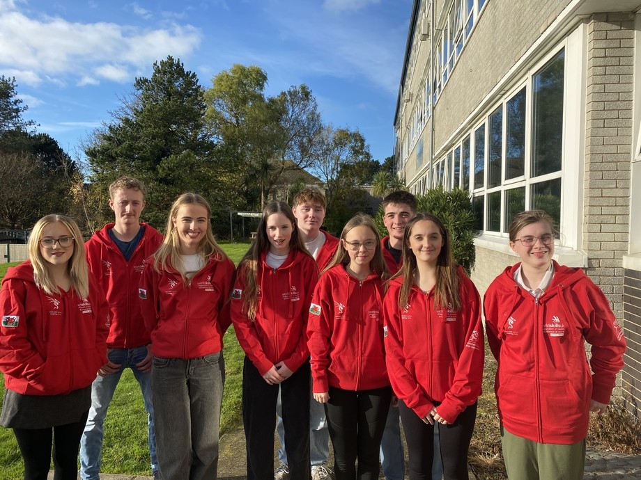 A group of students in red competition hoodies standing together, smiling