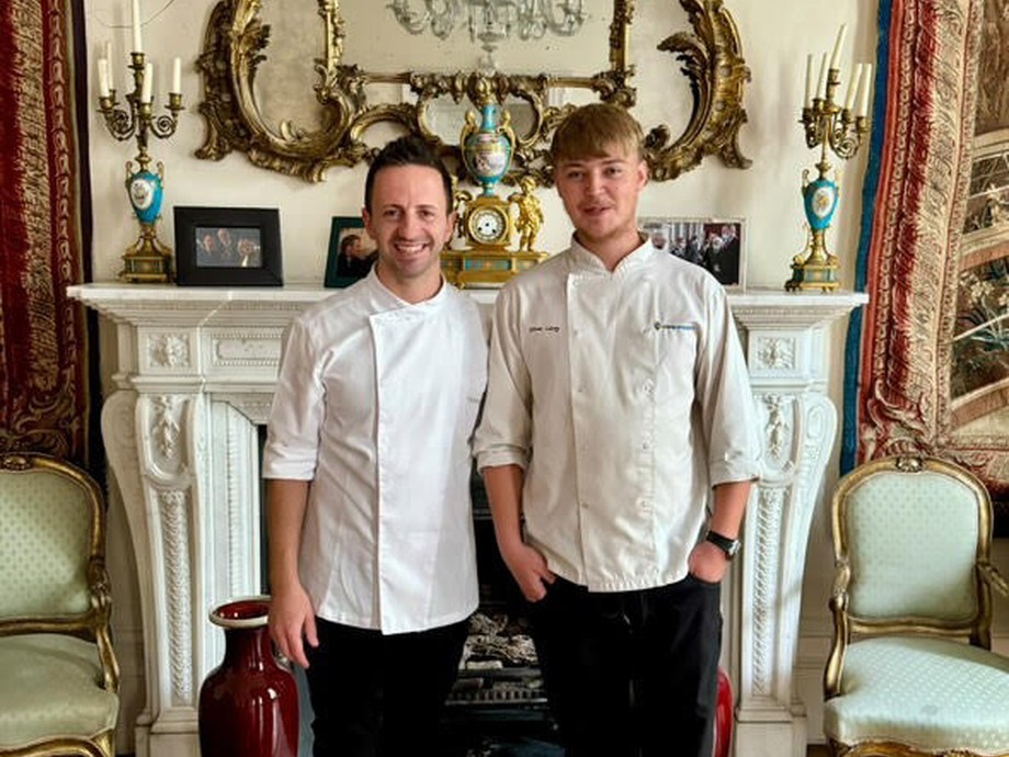 Oliver standing with the Italian chef in a very plush room 