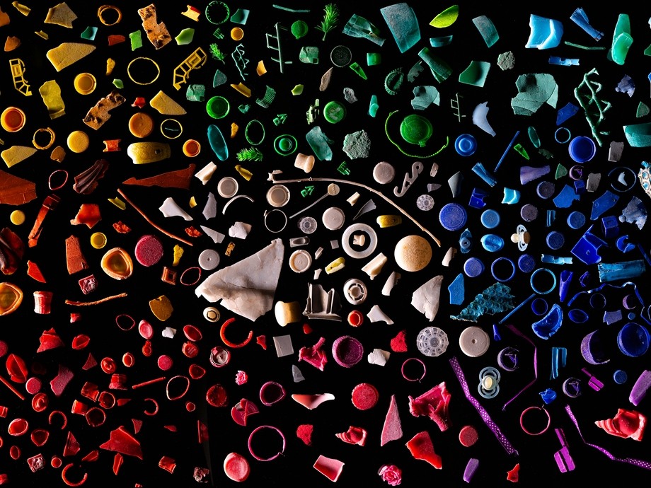 close up image of lots of pieces of micro plastics, arranged by colour on a black background, like a mosaic