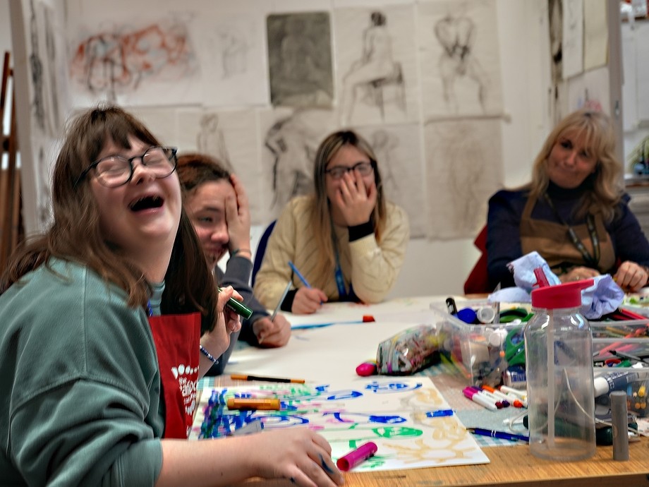 Students and their teacher around a table with one student laughing in joy