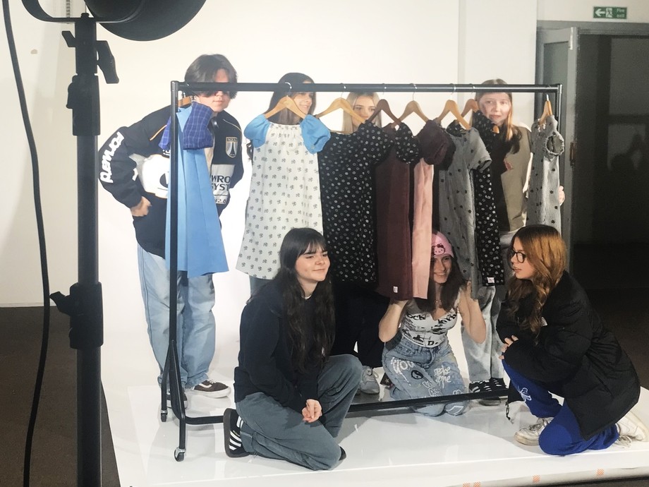 Students standing by a clothes rail on an area used to take photos