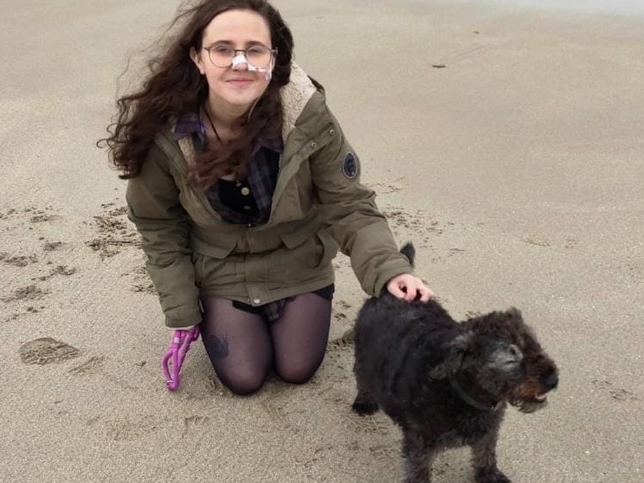 Rebecca crouched down on the beach with her dog