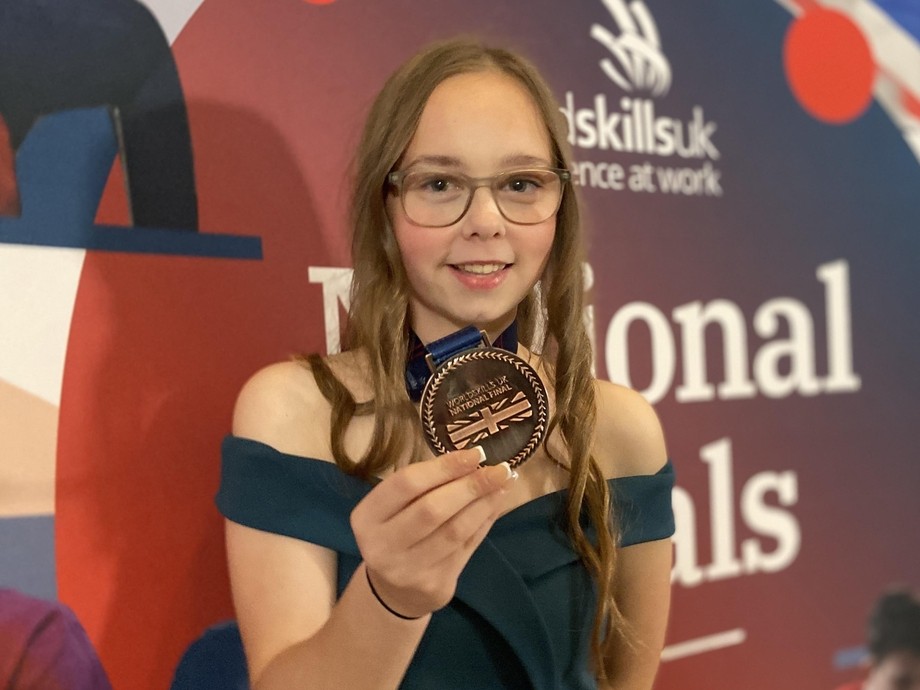 Shannon holding her bronze medal with a WorldSkills UK backdrop