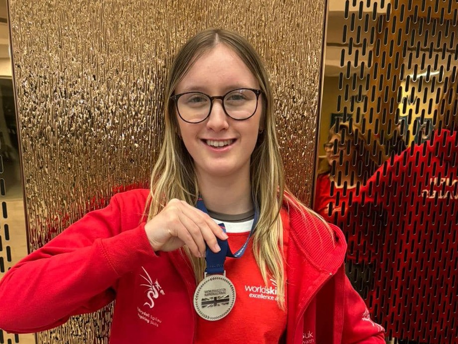 Evanna holding up her medal in her red Welsh hoodie