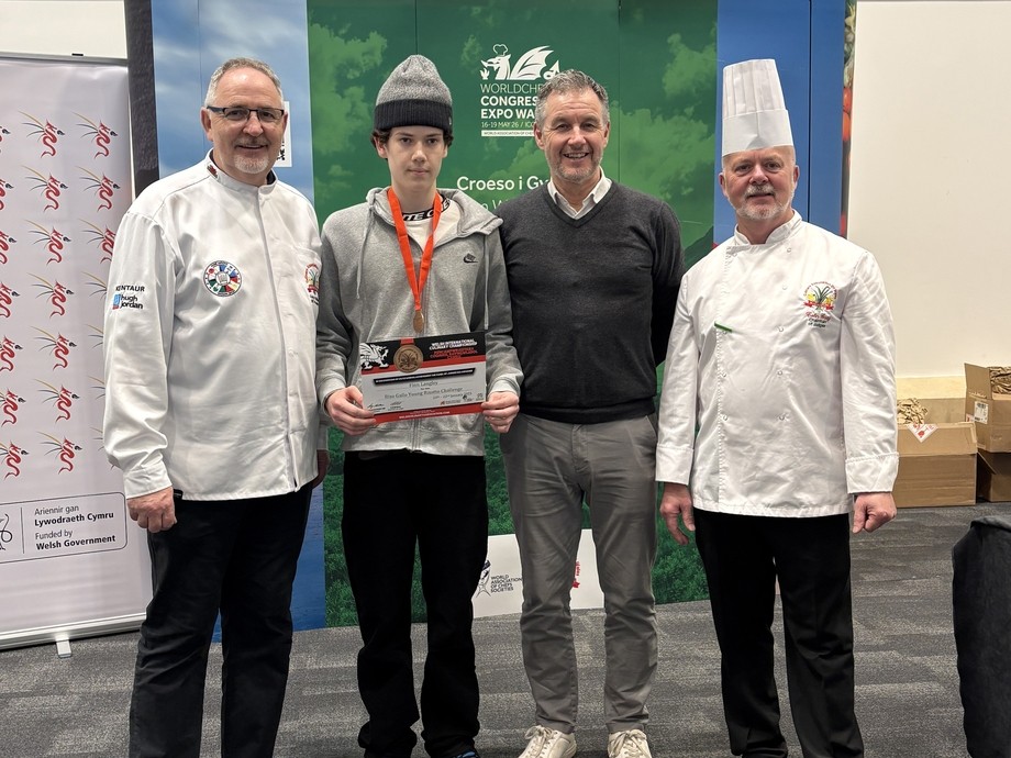 Finn standing with chefs wearing a competition medal