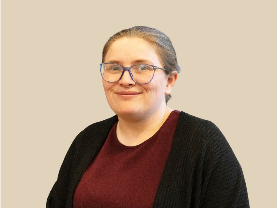 Karen wearing a mauve top and black cardigan with a plain background looking at the camera
