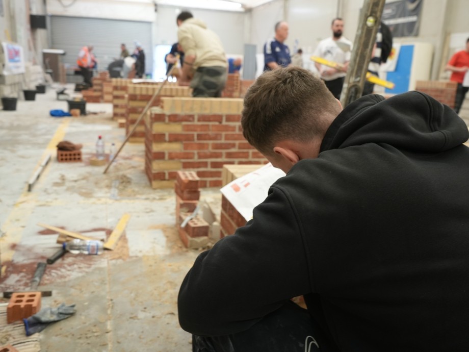 A student working with bricks with the competition in the background
