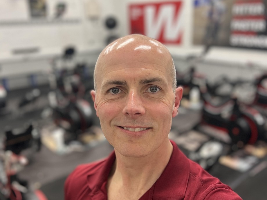 Rob Kirk in a maroon top with a blurred weights background