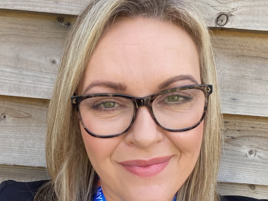 Val Morse headshot wearing glasses, blond/brown hair in a green top