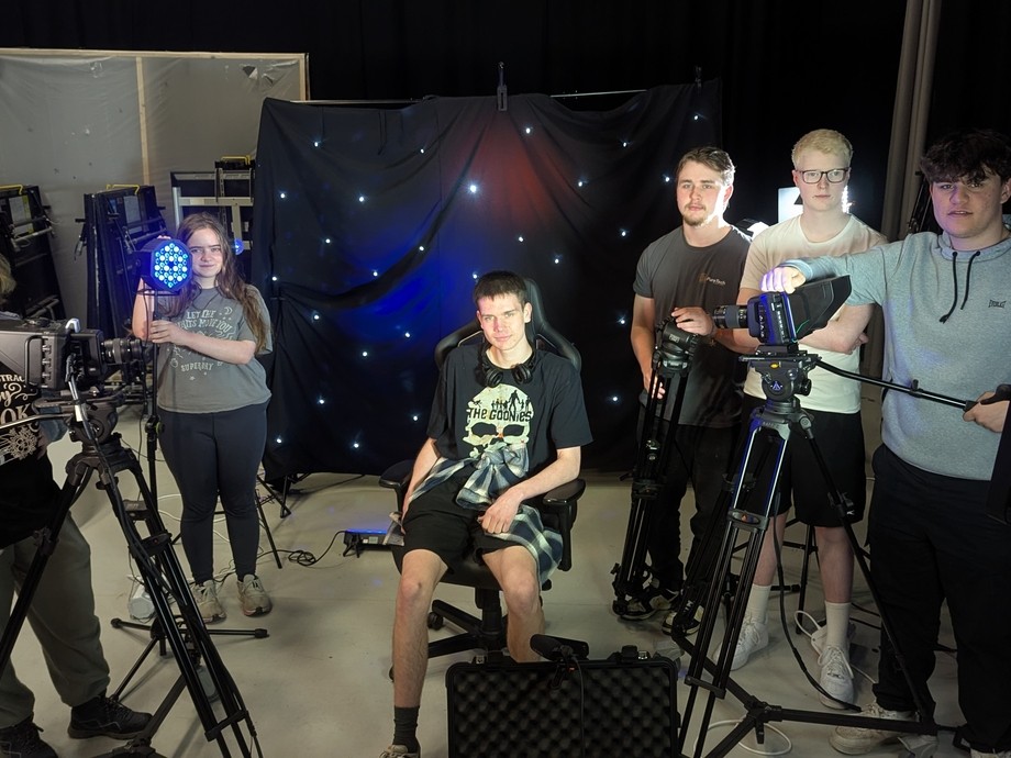 A group of students next to various apparatus in the college media studio