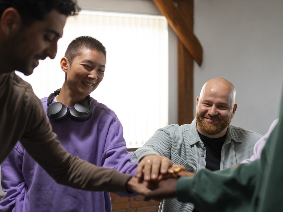 group therapy session - everyone has their hands together in the middle of the circle