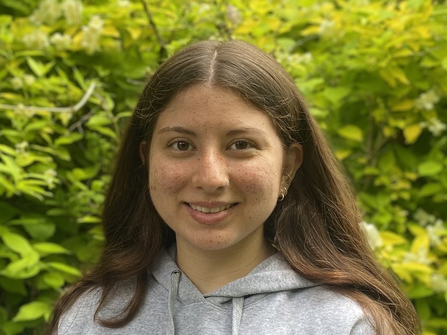 Hannah in front of some greenery wearing a Princeton hoodie