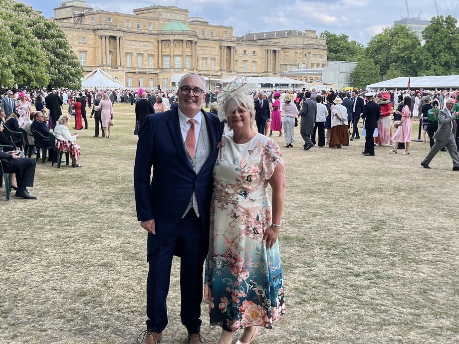 Rob and his wife Michele standing together in grassy grounds behind Buckingham Palace