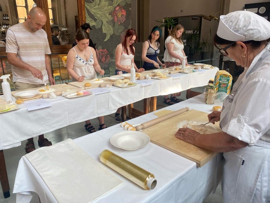 An Italian lady demonstrating pasta making with students ready at their stations