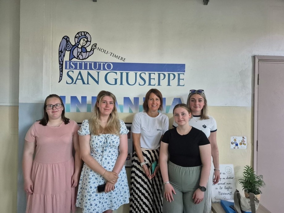 Five students standing under an Italian sign indoors