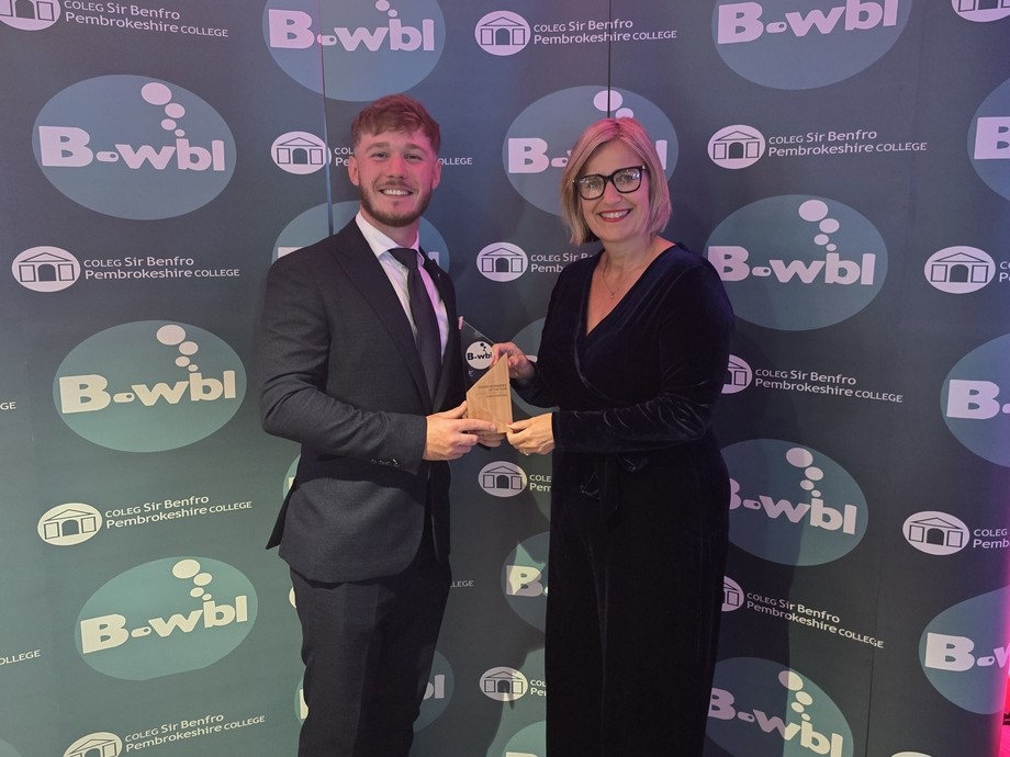 Euan with Vanessa Cashmore, Vice Principal receiving his work based learning award against a logo branded backdrop