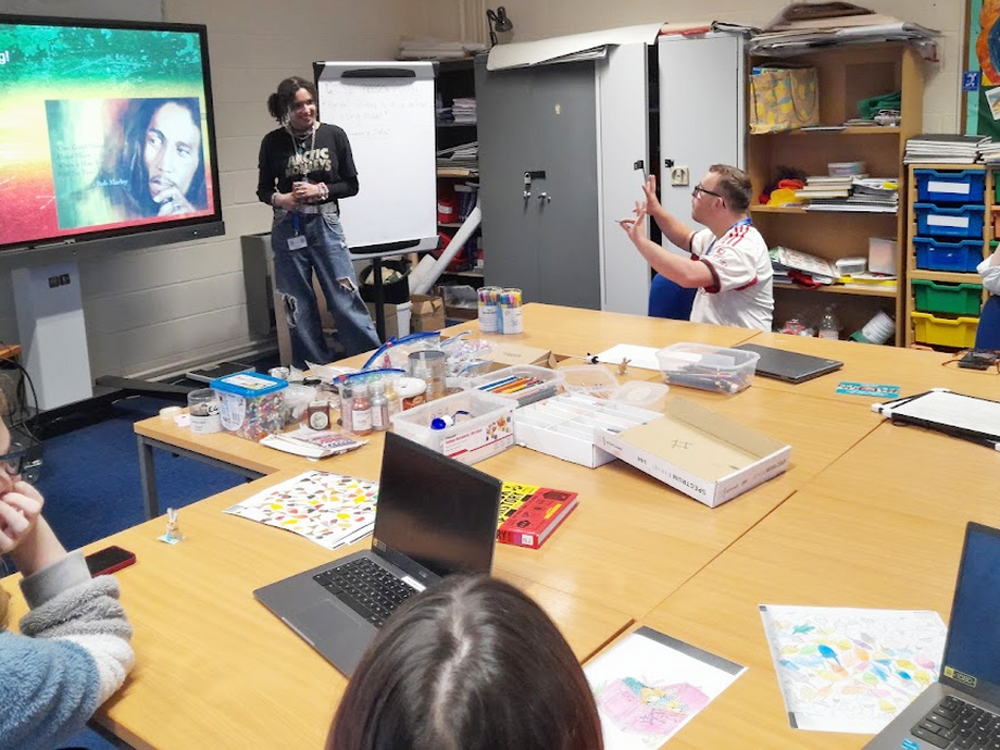 Ace in a classroom with people listening around tables