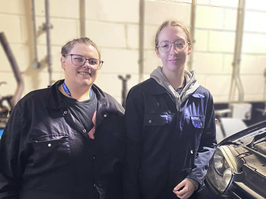 Lily and Sophie standing next to each other in the motor vehicle workshop