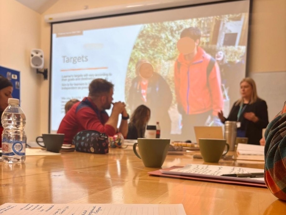 PGCE students at desks at Coleg Elidyr with a screen behind and someone talking