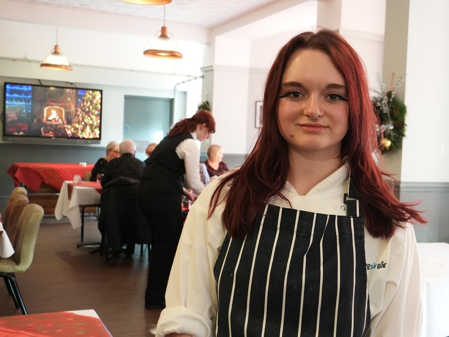 Erin in the restaurant wearing a stripy apron 