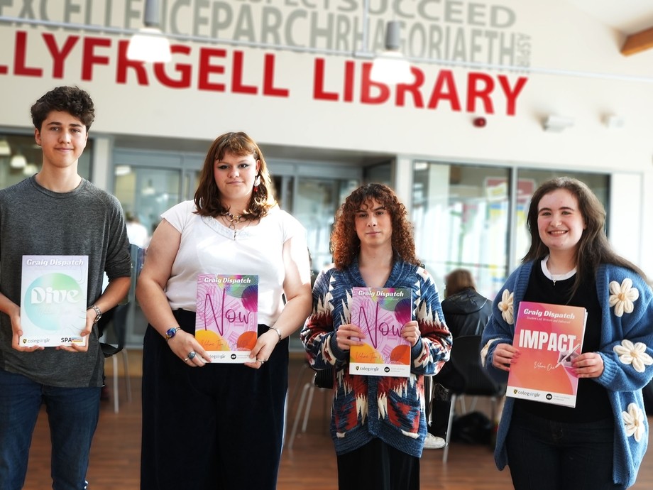 Four members of the team in a row each holding and edition of the magazine they are in Starbucks