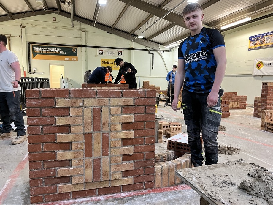 The winner of third place standing in the competition workshop with his finished brickwork