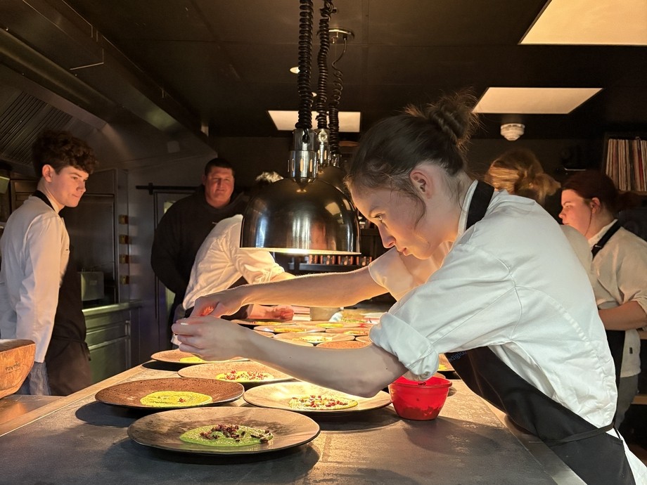 Students at the pass, plating up food with low lighting  