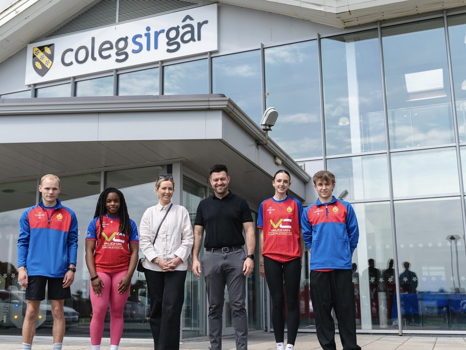 Six people lined up outside the college with logo showing. They are sports students with Vaughan Constructions reps (sponsors)