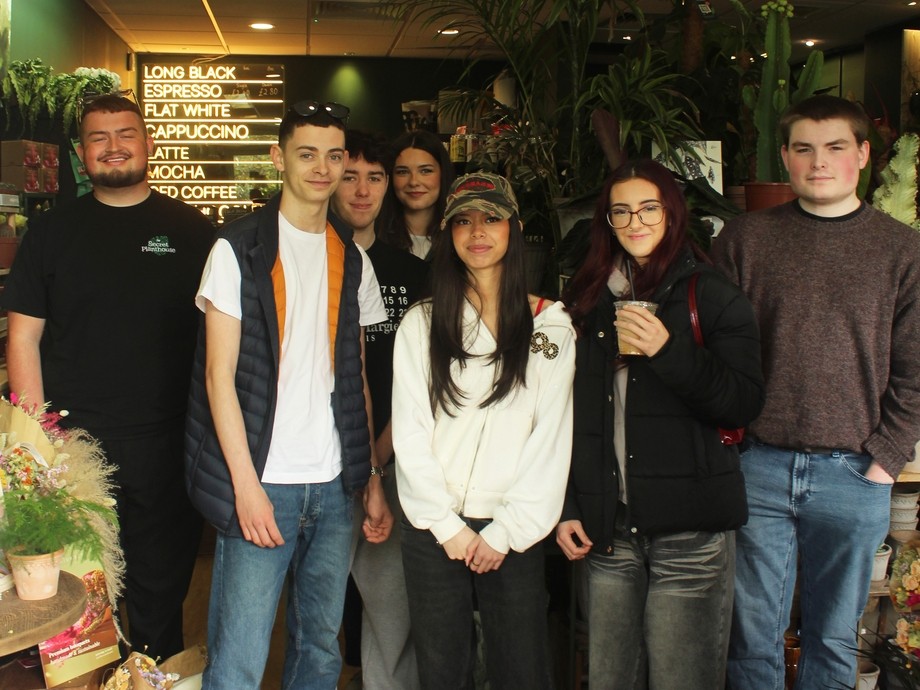Students in the Secret PlantHouse shop standing in a line with Cameron the owner in a dimly lit calm environment