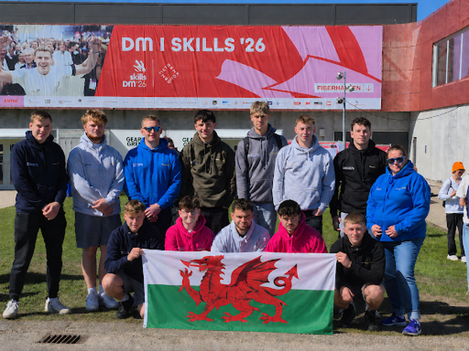 Students with a Welsh flag in front of a banner saying skills (a banner for the event)