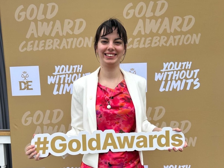 Lowri holding a gold awards sign in front of DoE branding