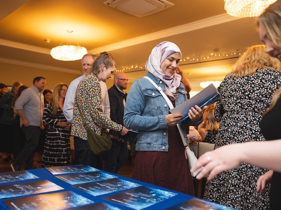 A crowd gathering for the awards focussed on the table where they pick up the awards brochure