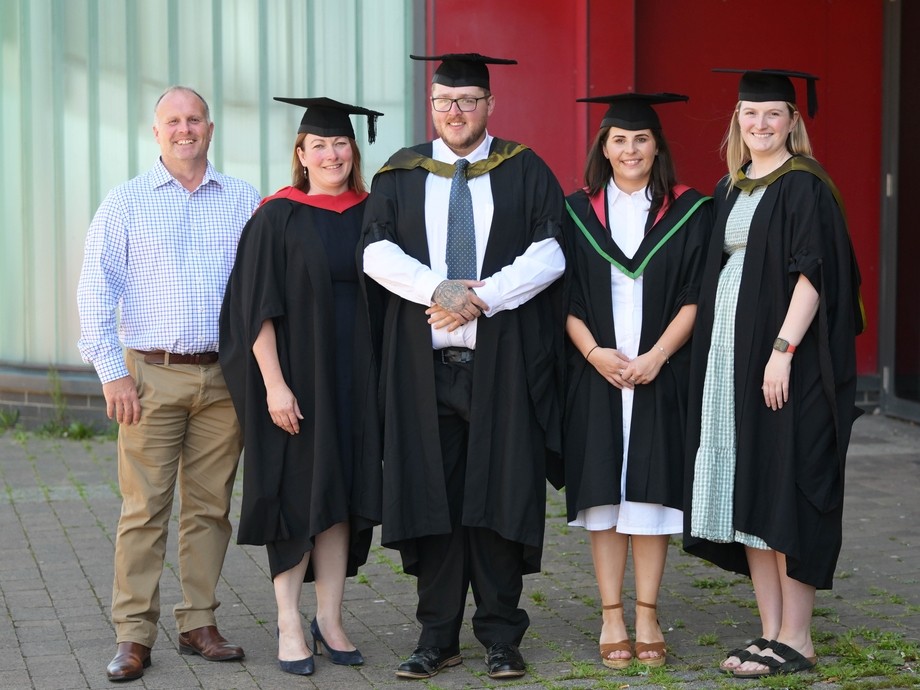 Keal standing in a line with his lecturers they are all wearing cap and gowns
