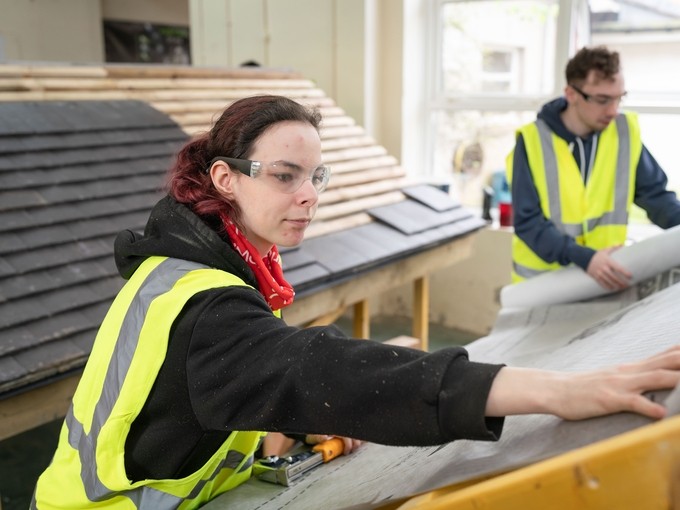 Two students practicing roofing skills in a workshop.