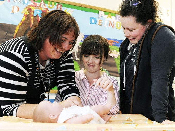 A lecturer with a student demonstrating on a baby learning mannequin