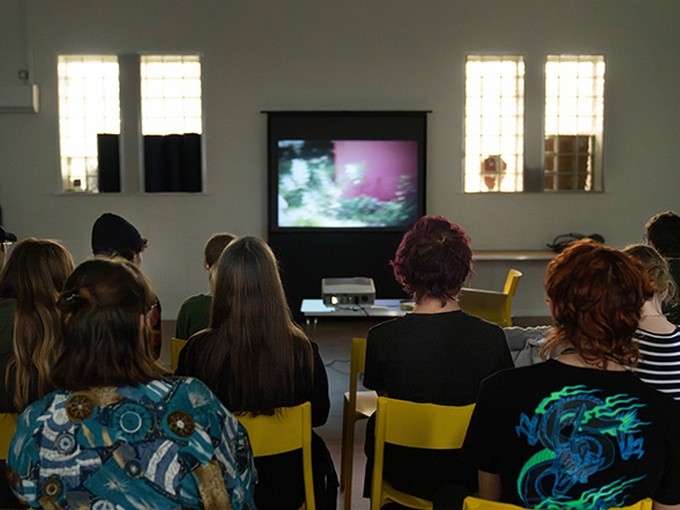 Looking from behind, a group of people watching a presentation