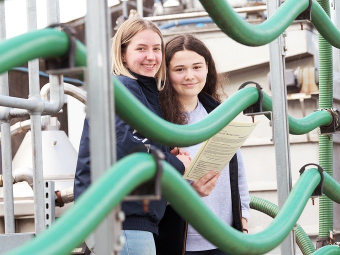 two girls standing behind green bendy railings