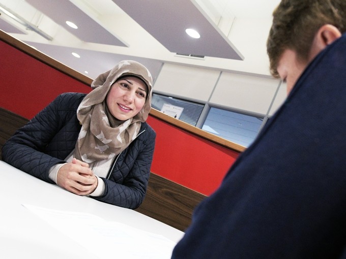 a woman in a headscarf sitting against a red background