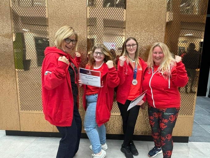 Two staff and students all wearing red with their fists up in sign of celebration
