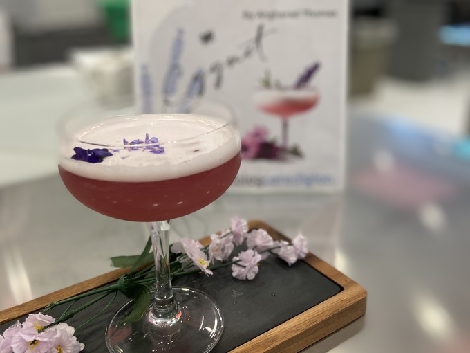A picture of the lavender cocktail it's purple and in a wide champagne glass, it's well presented for judging