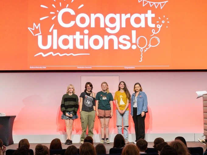 Students under a 'congratulations' sign at the exhibition