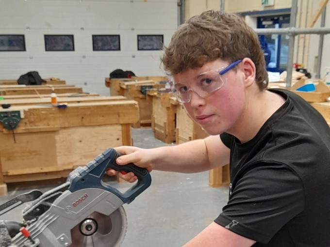Ethan using some carpentry equipment in the workshop