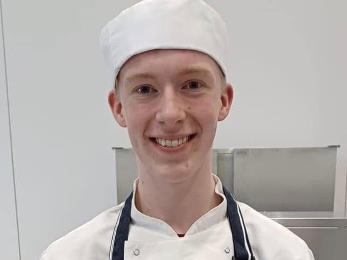 Harry holding his risotto in a chef uniform