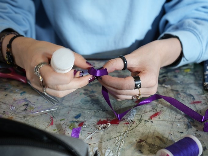 hands making item with purple ribbon