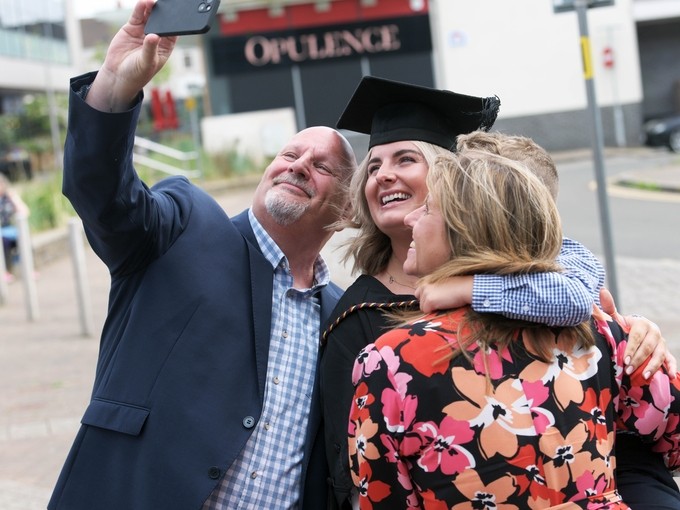 A family taking a celebratory selfie at graduation.