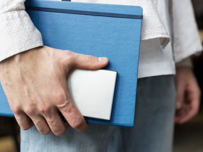 close up of hands holding a notebook and phone