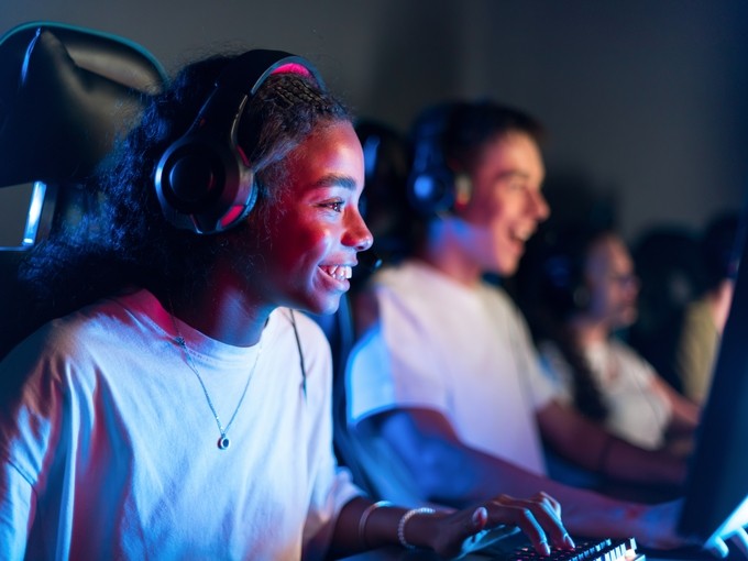 black-teen-smiling-girl-headset-playing-video-games-video-game-club-with-blue-red-illumination-keyboard-with-illumination