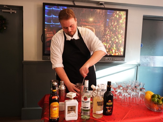 A student behind a table with loads of cocktail ingredients and shakers