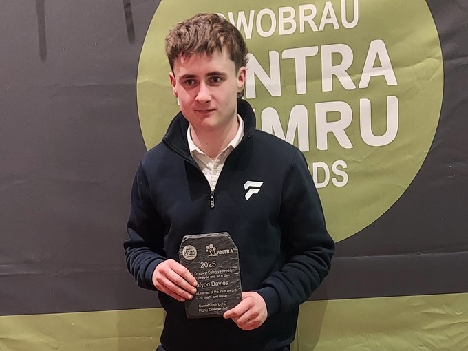 Dafydd standing with his Lantra award in front of Lantra Cymru branding
