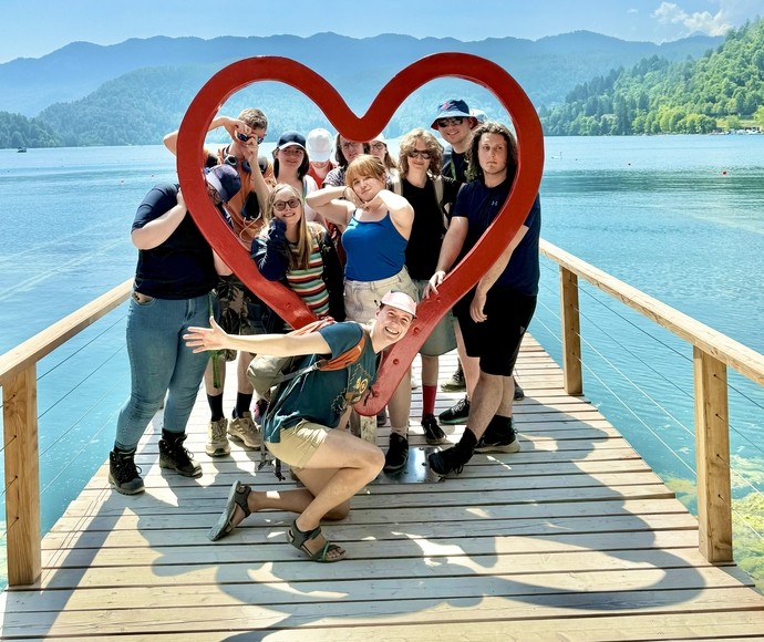 Students on a jetty with a large heart posing for photo